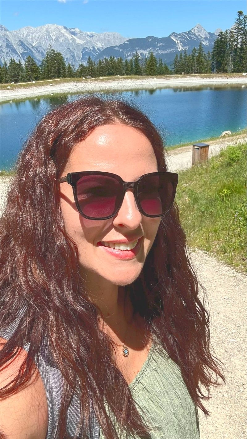 Tina Kauert lächelt an einem Bergsee in den Alpen