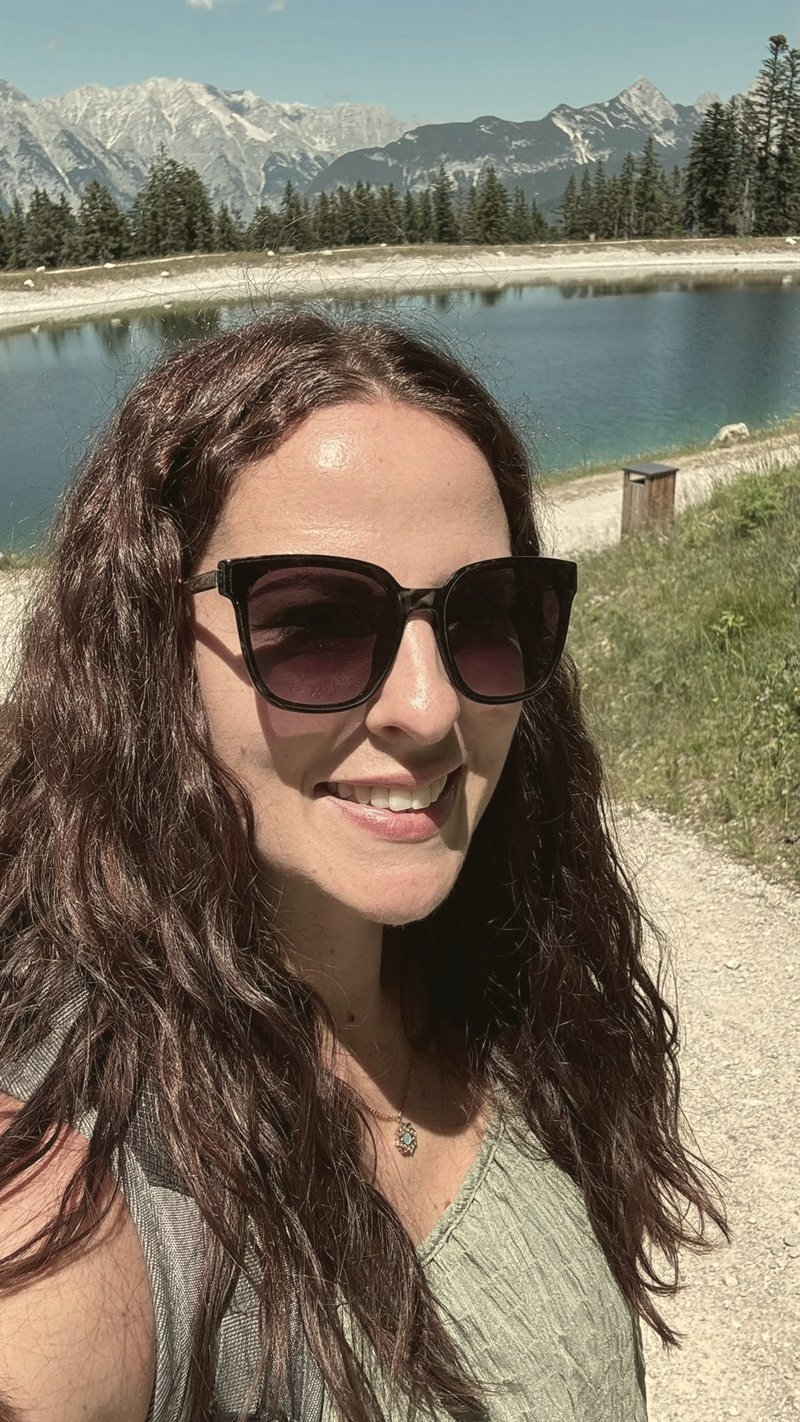 Tina Kauert lächelt an einem Bergsee in den Alpen